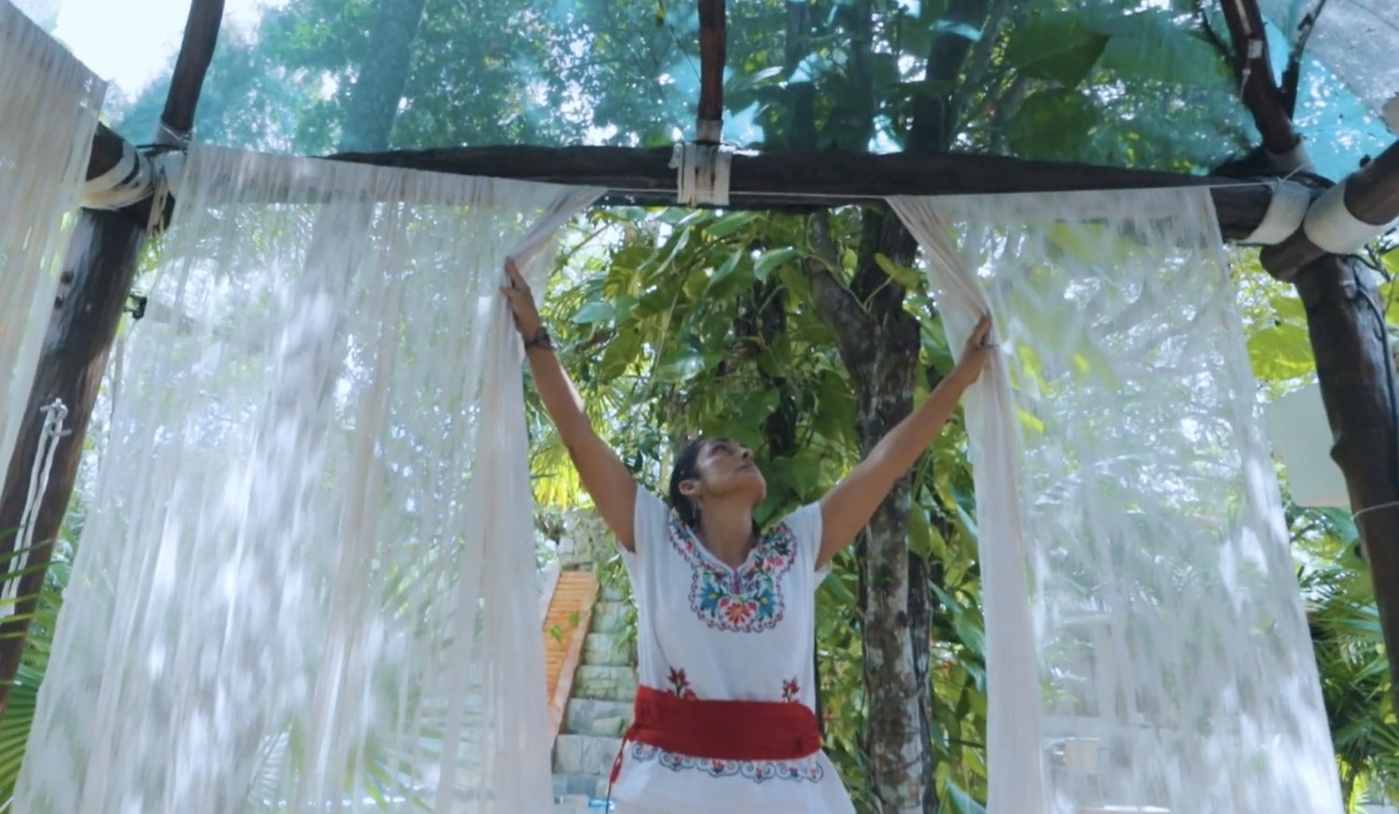 Mujer abriendo las cortinas de la palapa en OMA Cancún